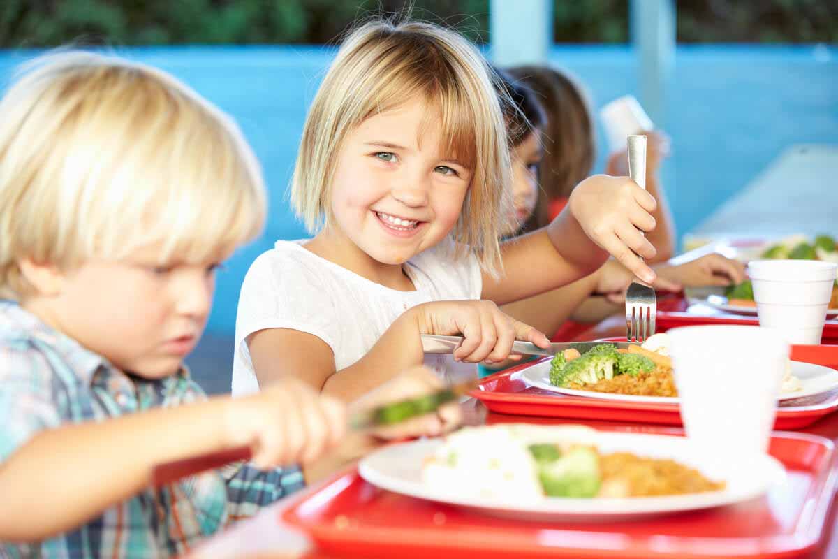 Elementary Pupils Enjoying Healthy Lunch In Cafeteria