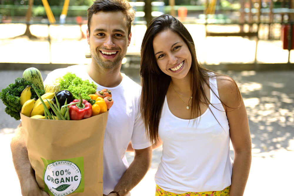 Happy couple carrying a bag of organic vegetables.