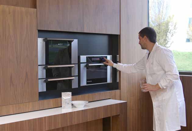 Hombre enciende horno para meter un vaso de agua a acalentar y tienen una encimera un sobre y un plato hondo