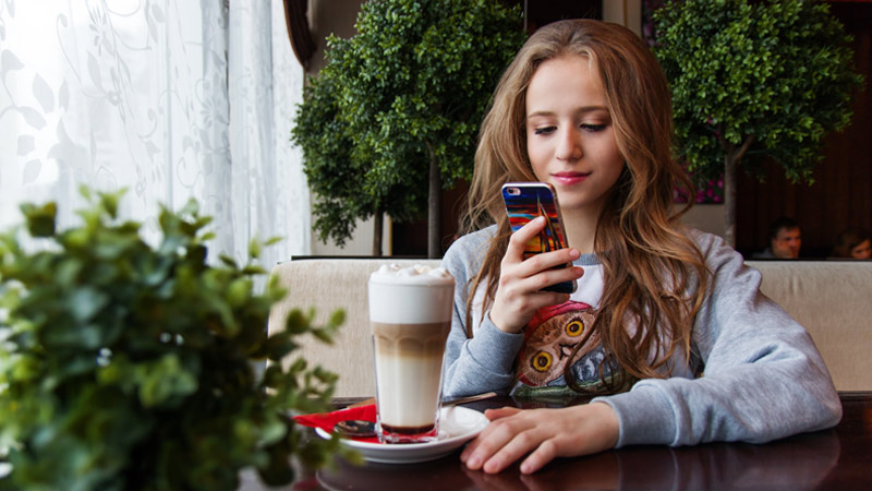 mujer mira telefono mientras toma cafe